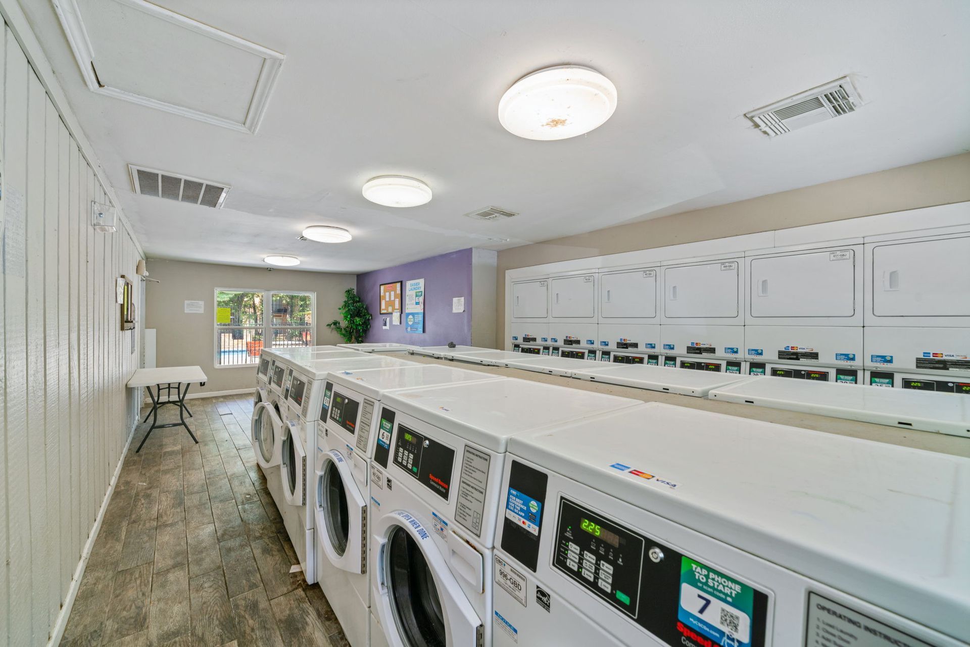 Laundromat with rows of washing machines, white walls, and bright overhead lights.