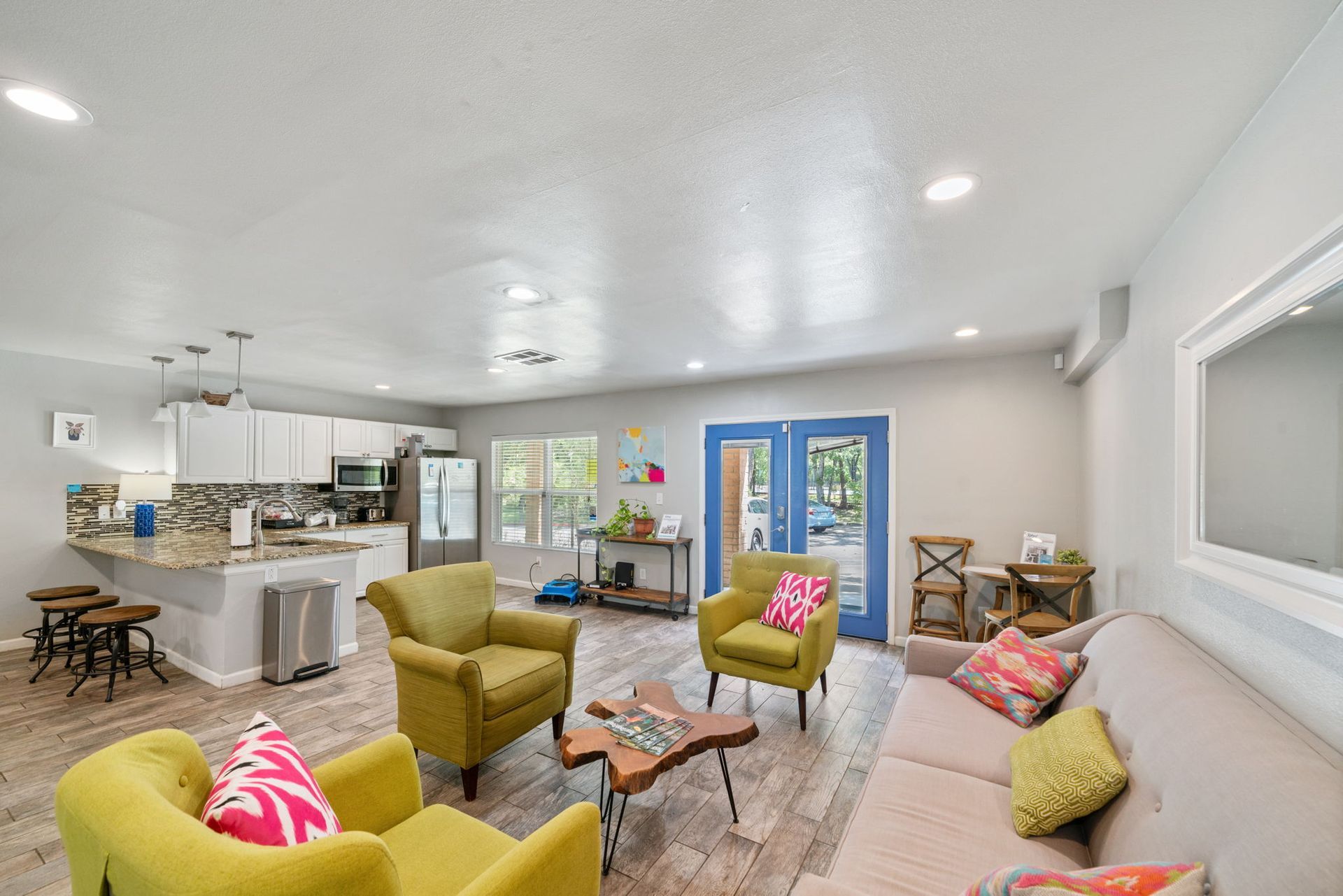 Open-concept living space with kitchen, seating area, and blue doors leading outside.