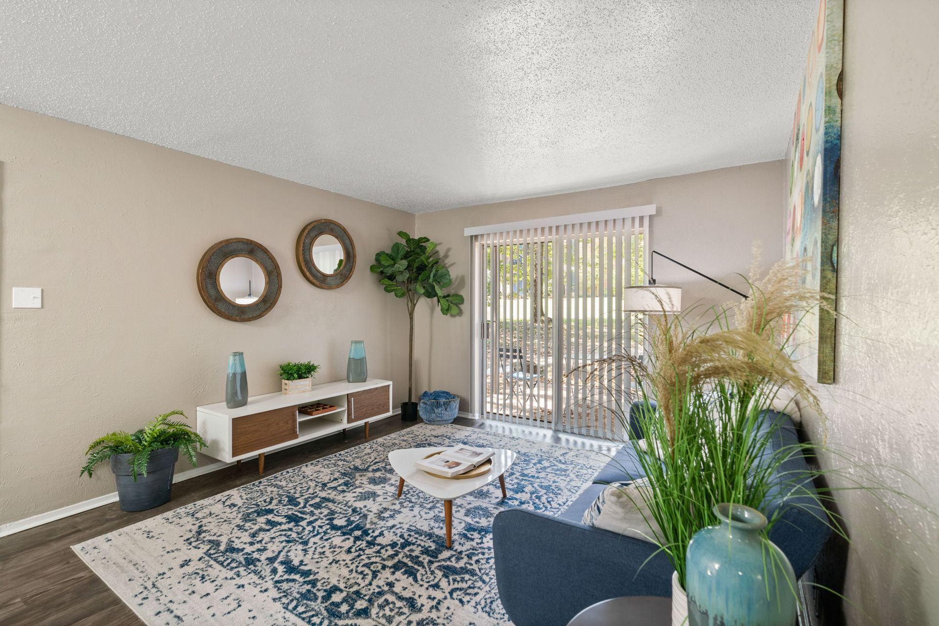 Living room with blue accents, rug, and modern decor, including a sliding door to the outside.