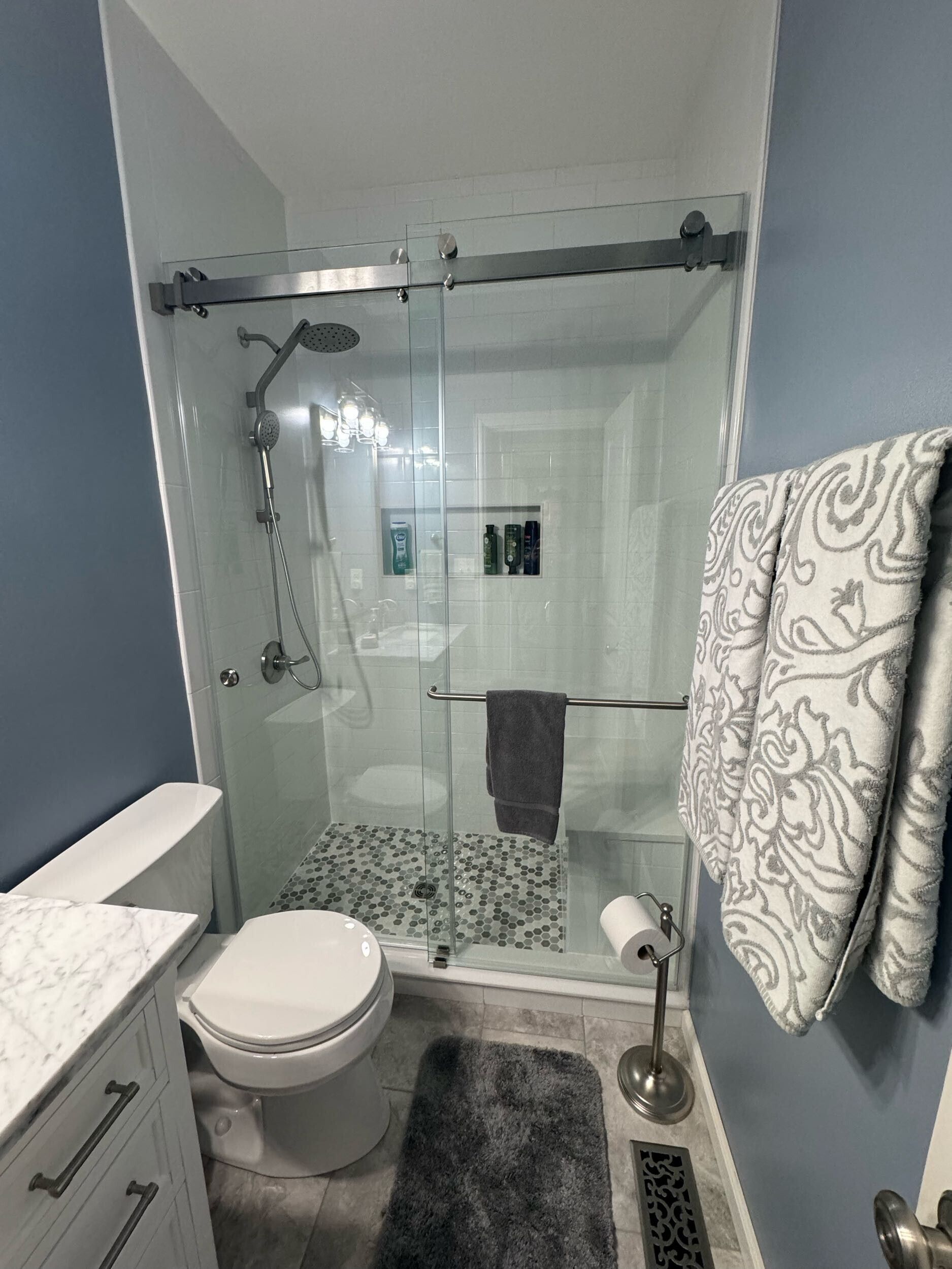 A bathroom with a toilet , sink , and shower with a sliding glass door.