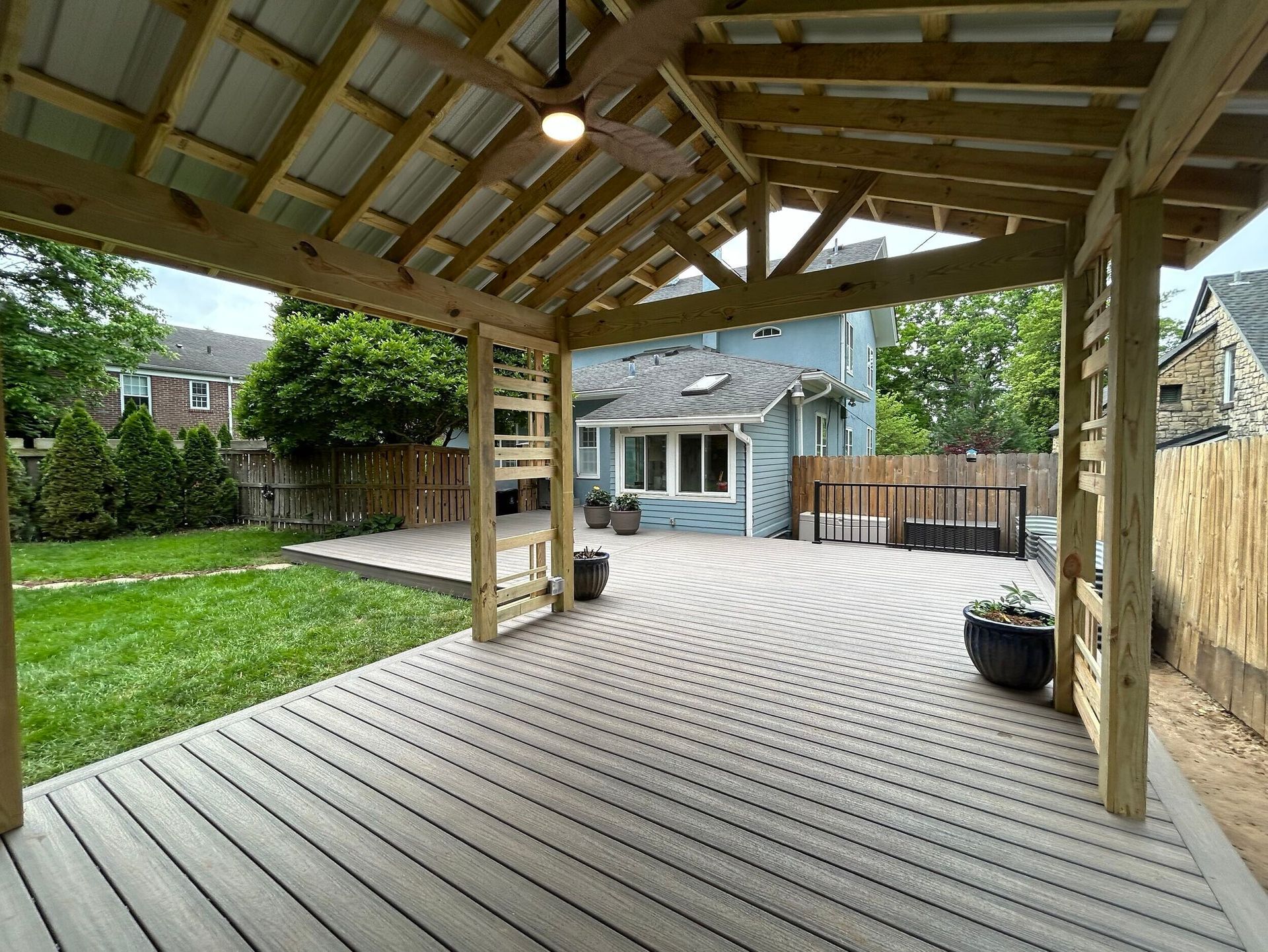Wooden patio with a gazebo, backyard with a circular paved area and green lawn.