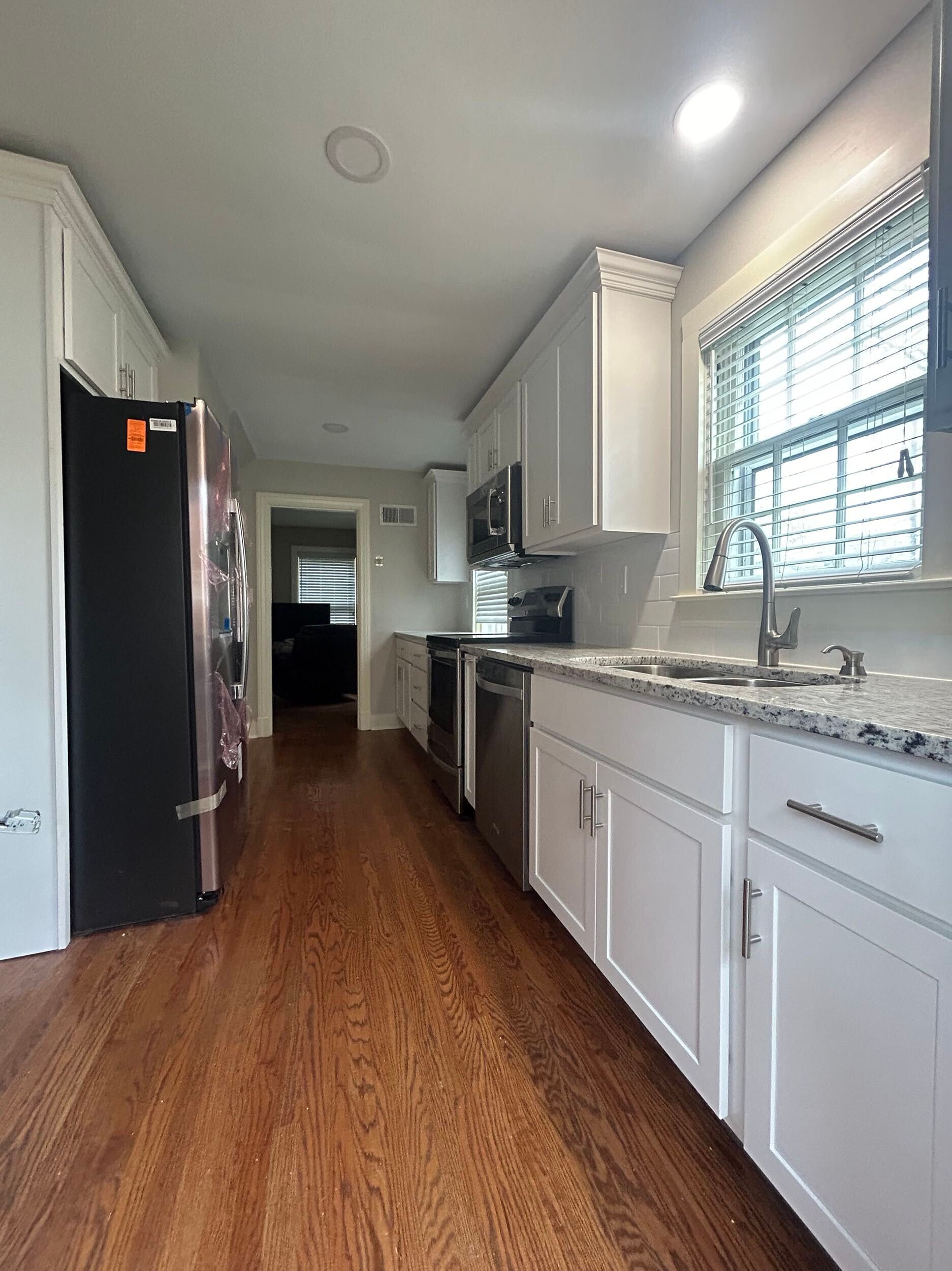 A long kitchen with white cabinets and granite counter tops