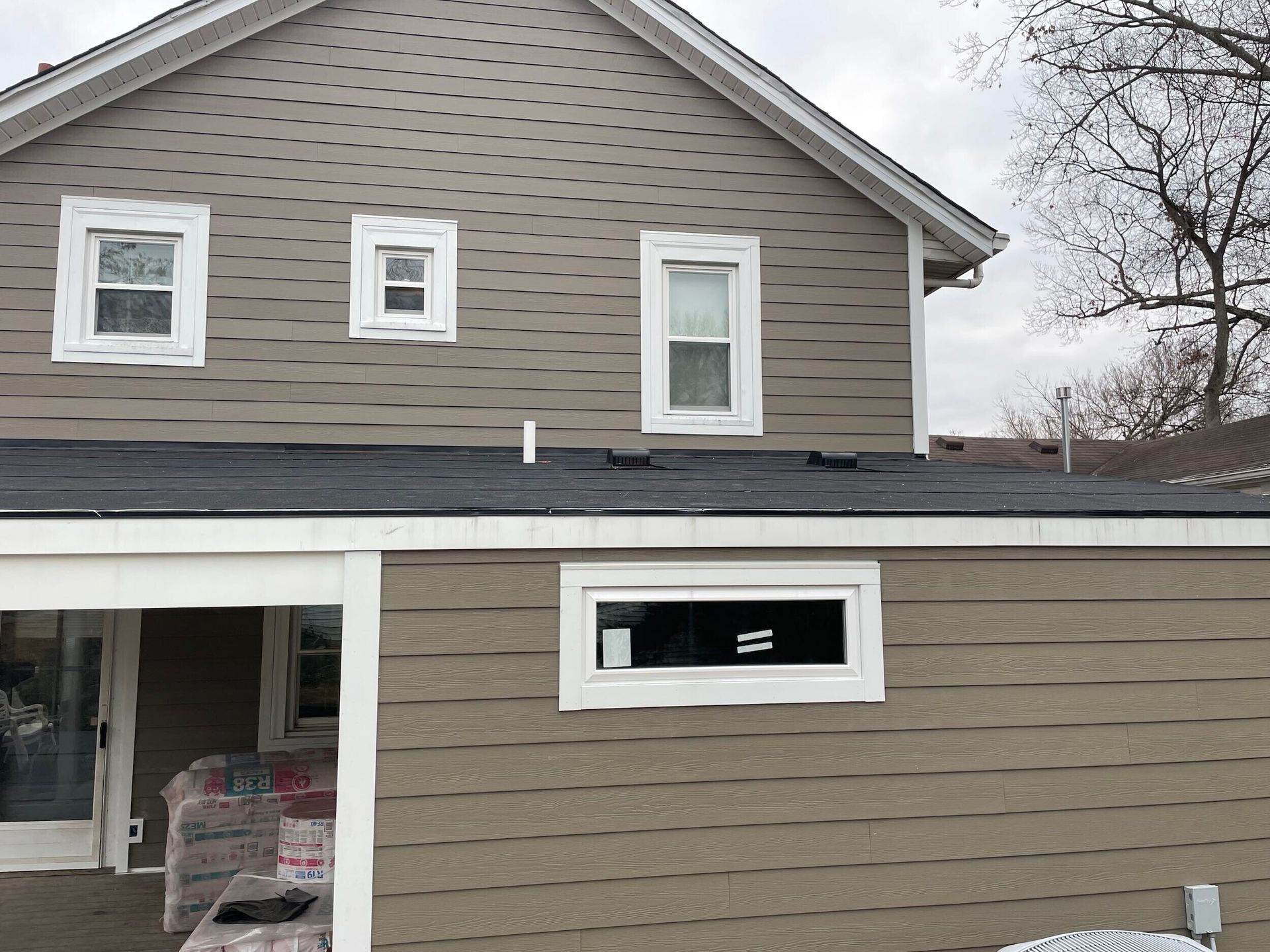 Beige house exterior with white-framed windows and dark roof. Snow on the ground.
