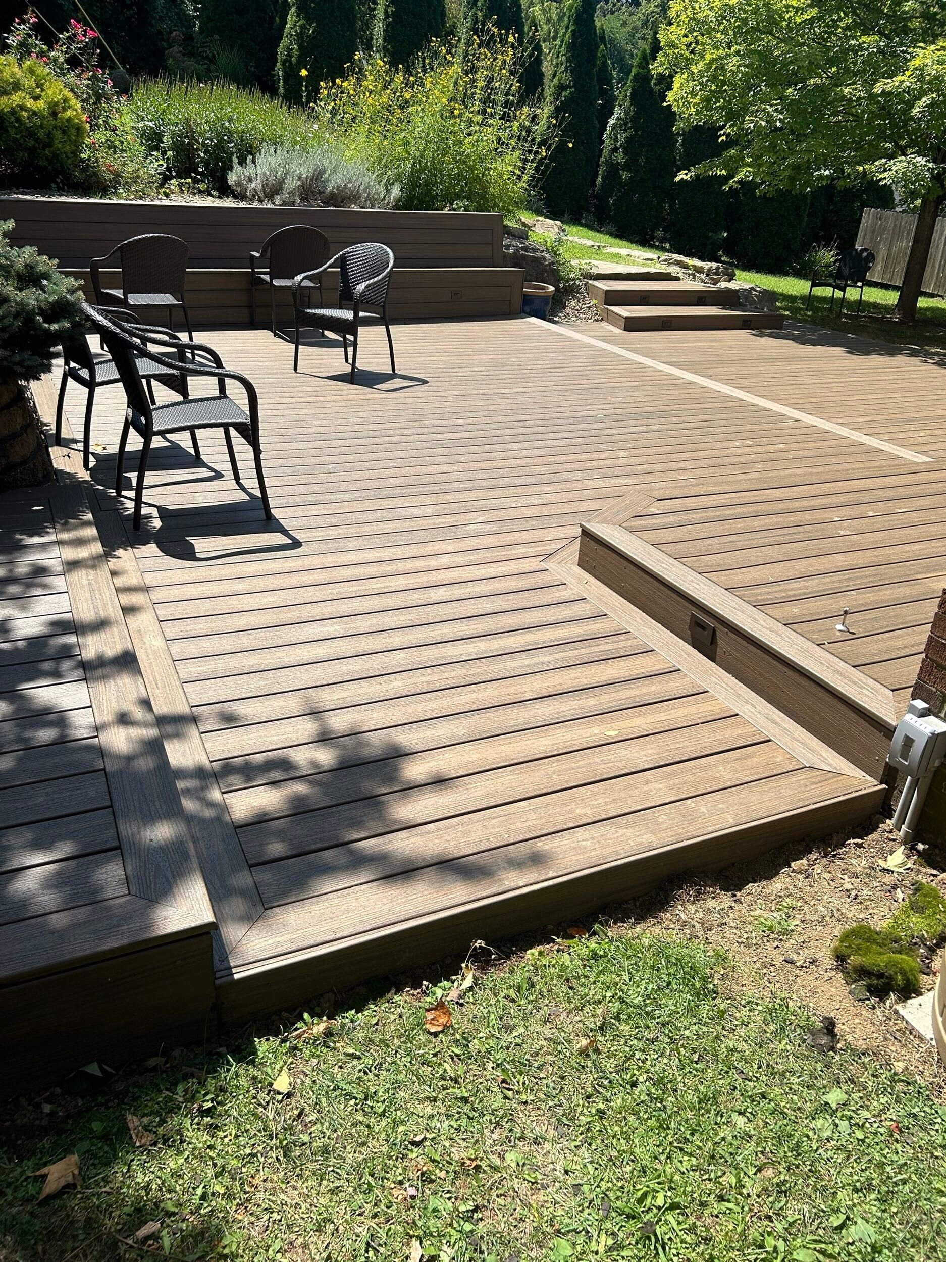 Outdoor patio with patterned paving, benches, and steps leading up to a landscaped garden area