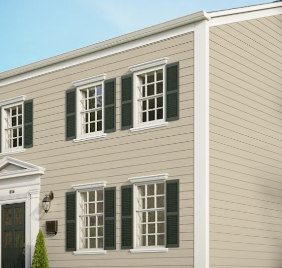 A beige house with green shutters on the windows