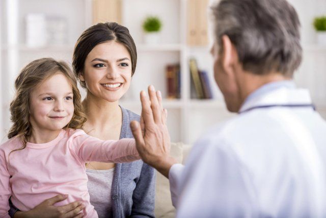 a woman and a little girl are giving a high five to a doctor .