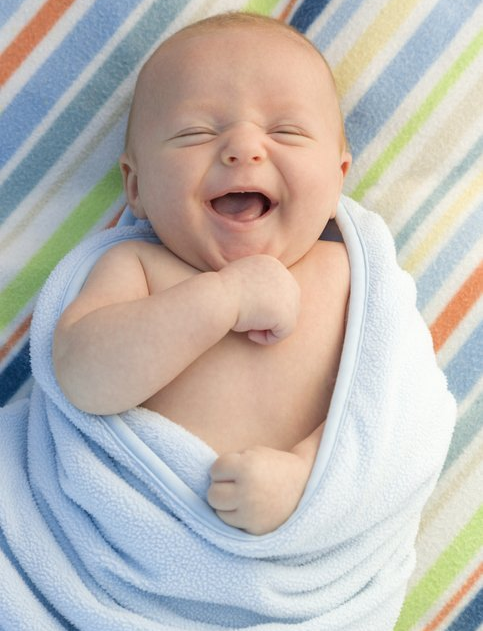 a baby wrapped in a blue blanket is laughing