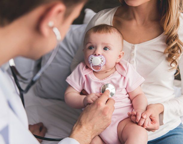 a baby with a pacifier is being examined by a doctor with a stethoscope .