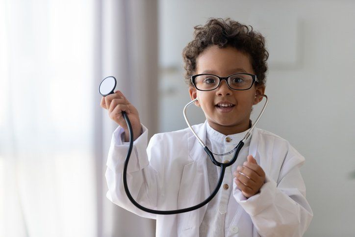 a young boy dressed as a doctor is holding a stethoscope in his hand .