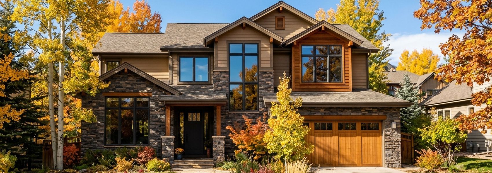 Upscale Colorado home with large windows framed by golden aspens on a clear autumn day
