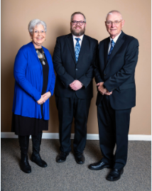 The front door of a house with a porch and plants in front of it.