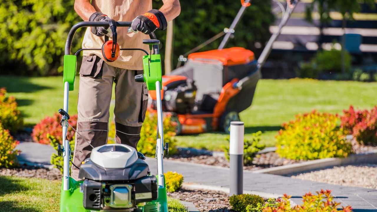 A man uses a lawn mower to neatly cut grass.