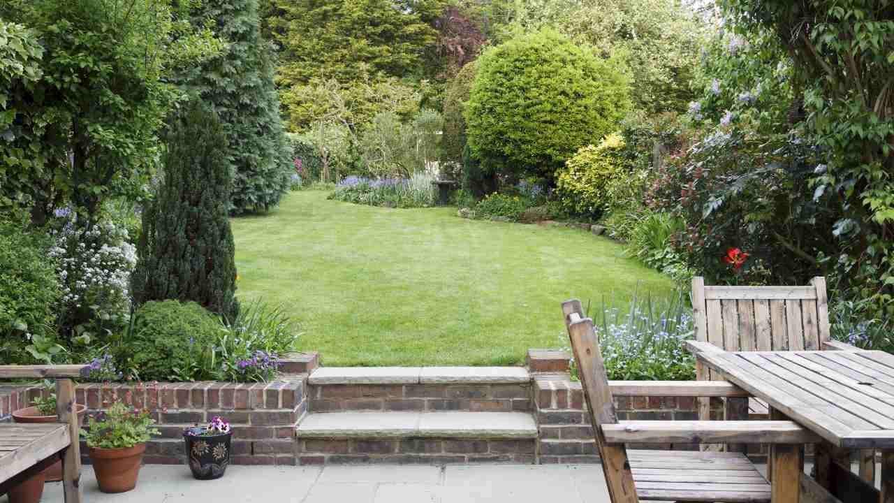 A garden with a table and chairs set on a lush green lawn.