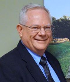 A smiling doctor in a lab coat with a stethoscope around his neck.