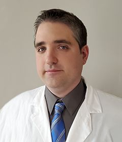 A smiling doctor in a lab coat with a stethoscope around his neck.