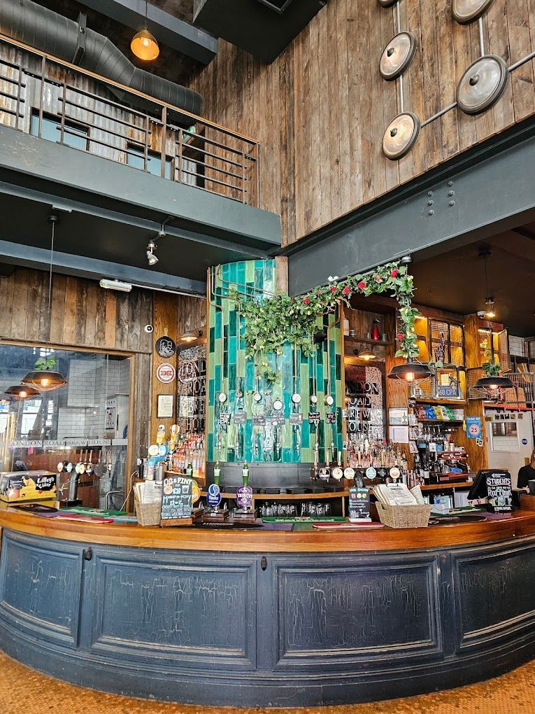 London Road Brew House, Southampton, view showing corner of ground floor bar with tiled wall to backfitting with craft beer dispense taps.