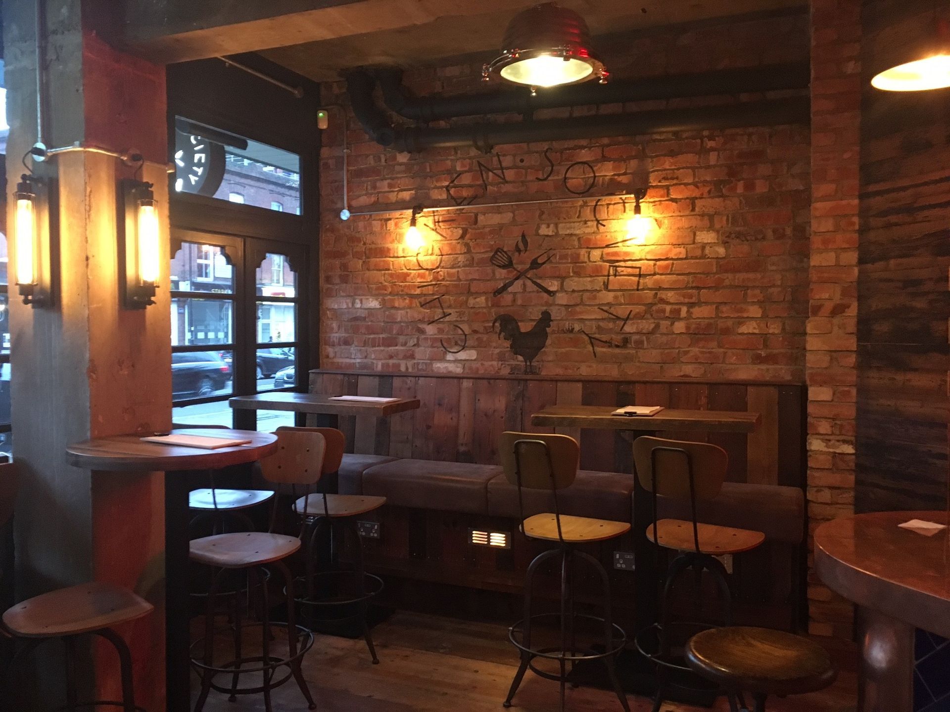 Chicken Society, Finchley, London, poseur height fixed seating in front of reclaimed brick wall near entrance.