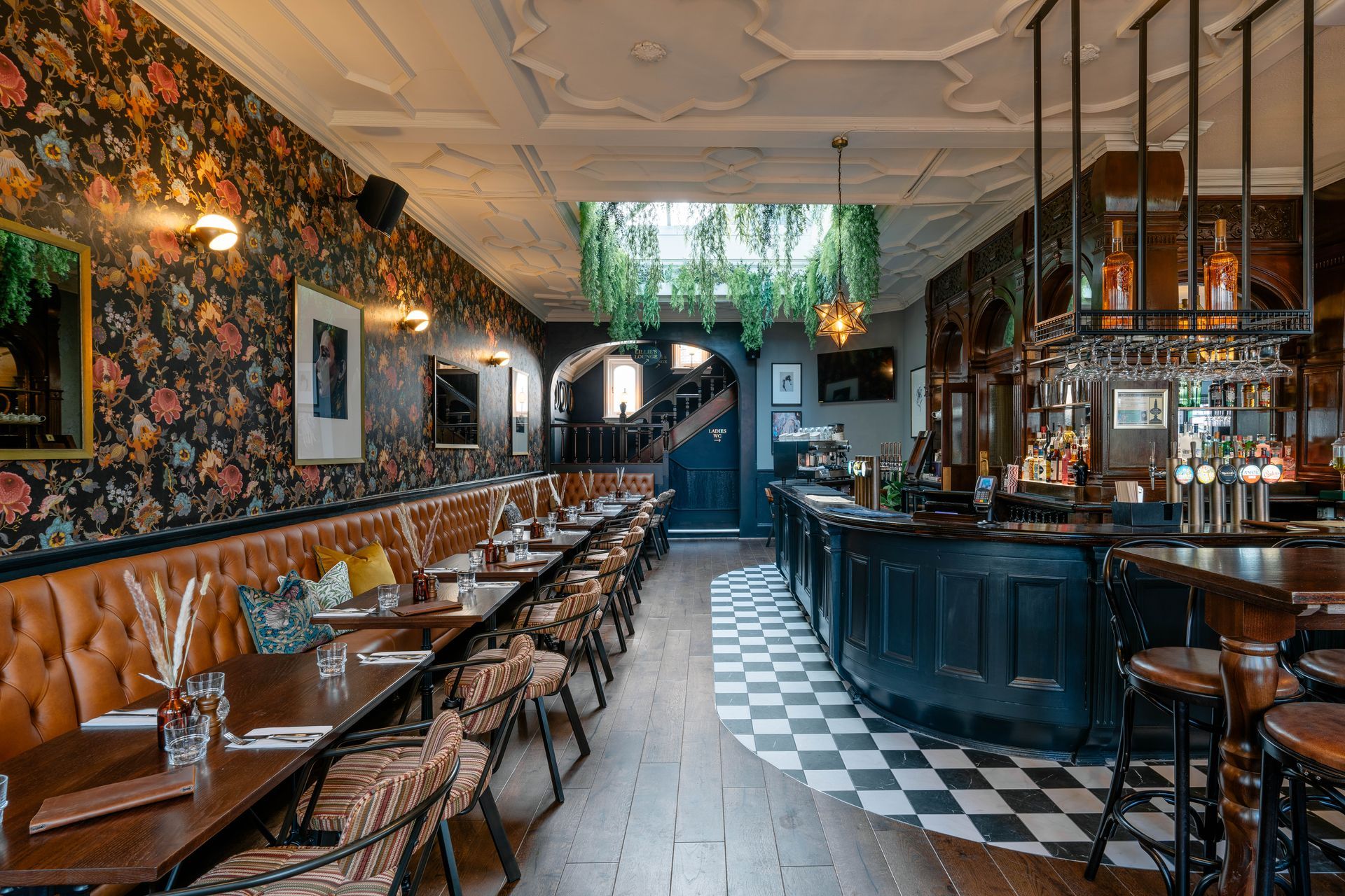 Lillie Langtry, Fulham, ground floor view towards bar counter, showing tiled bar walk, skylight with feature planting, and fixed seating opposite bar counter.