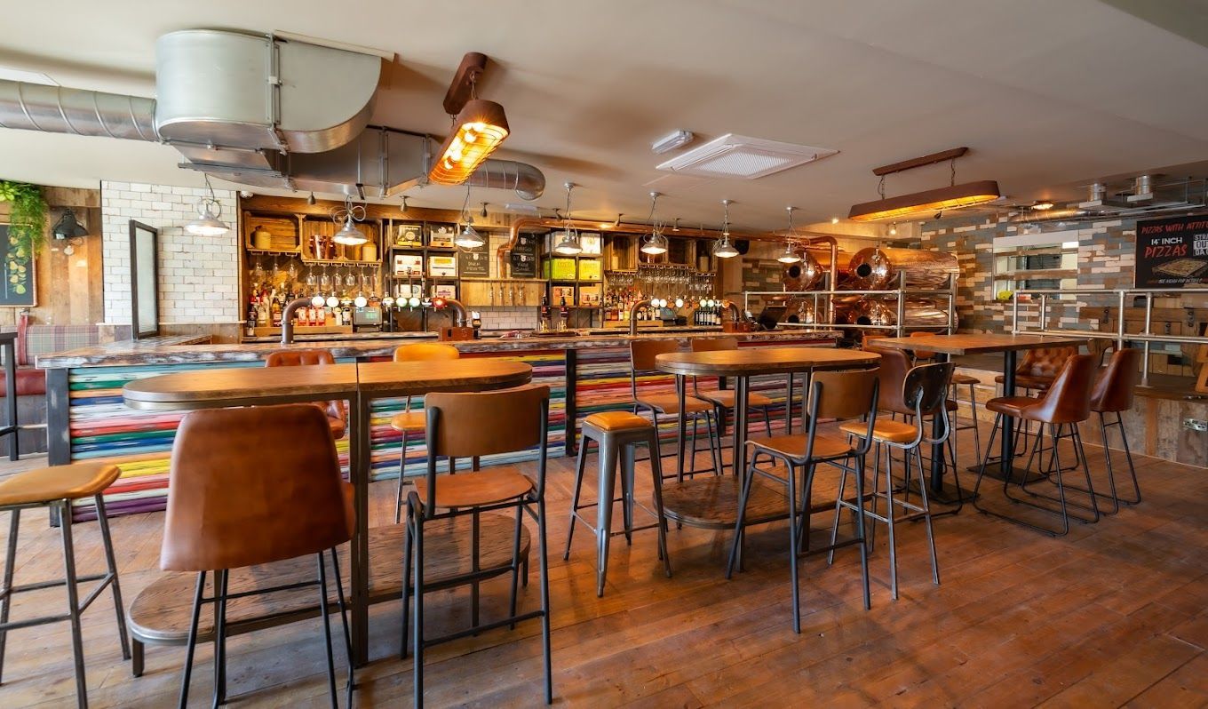 Bath Cider House, central vertical seating area in front of bar, industrial style furniture and timber flooring.