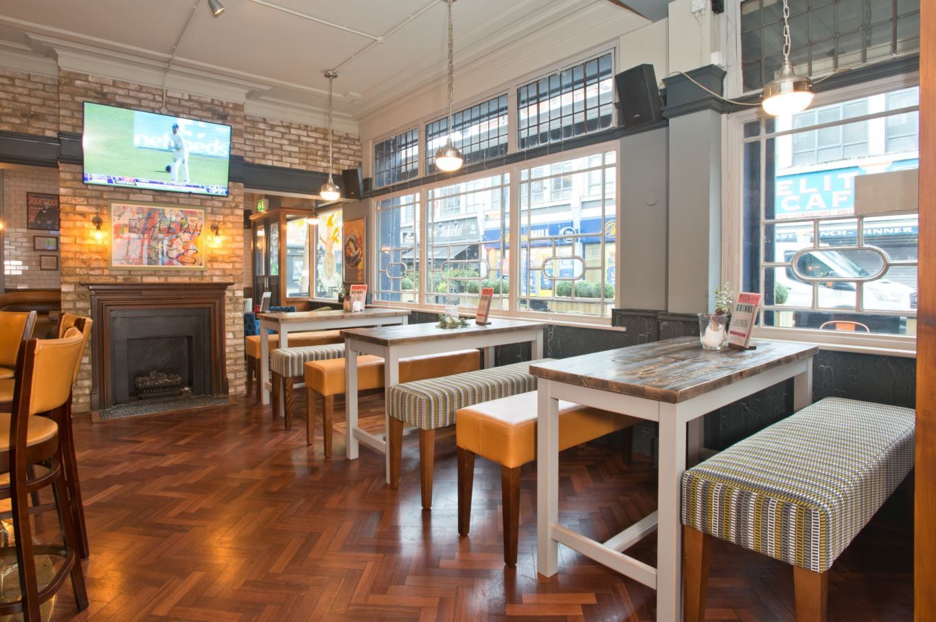 Whitecross Tap, Old Street, London,, ground floor high vertical seating area in front of windows, showing tables and upholstered benches.