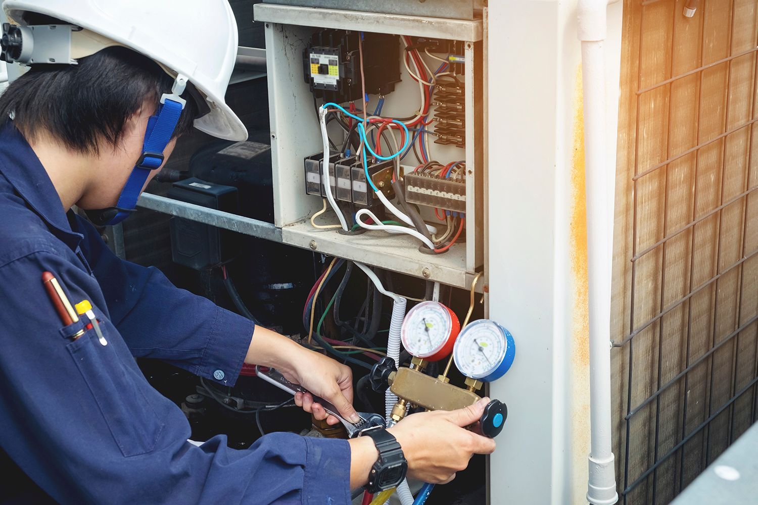 A man in a hard hat is working on an air conditioner.