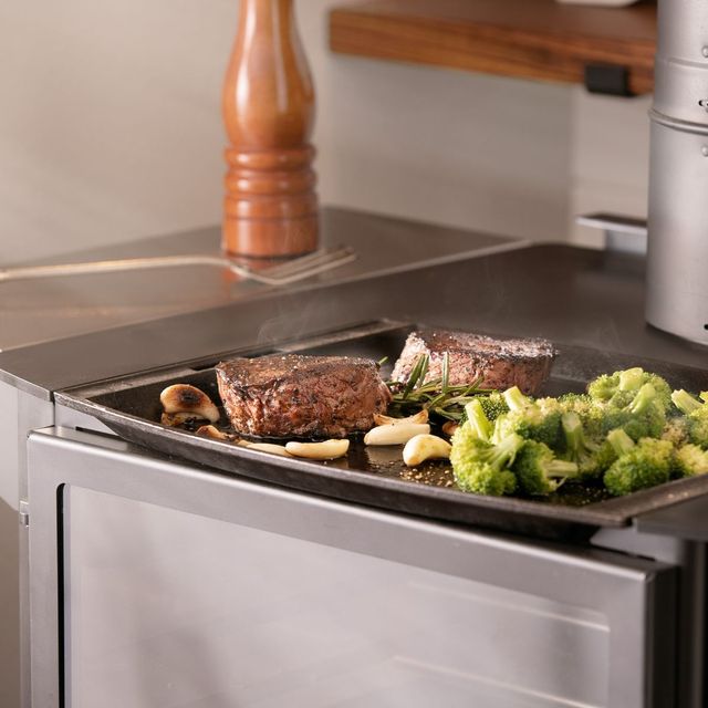 A steak and broccoli are being cooked on a stove top