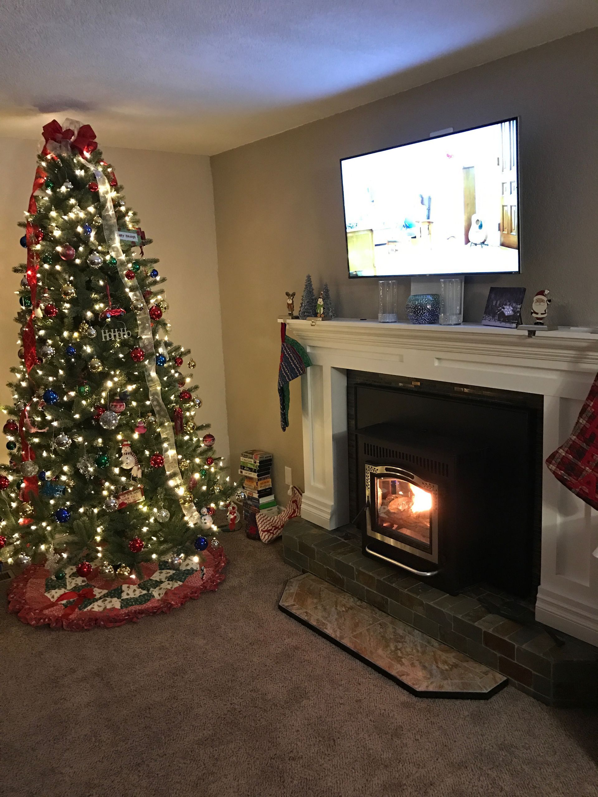 A living room with a christmas tree and a fireplace.