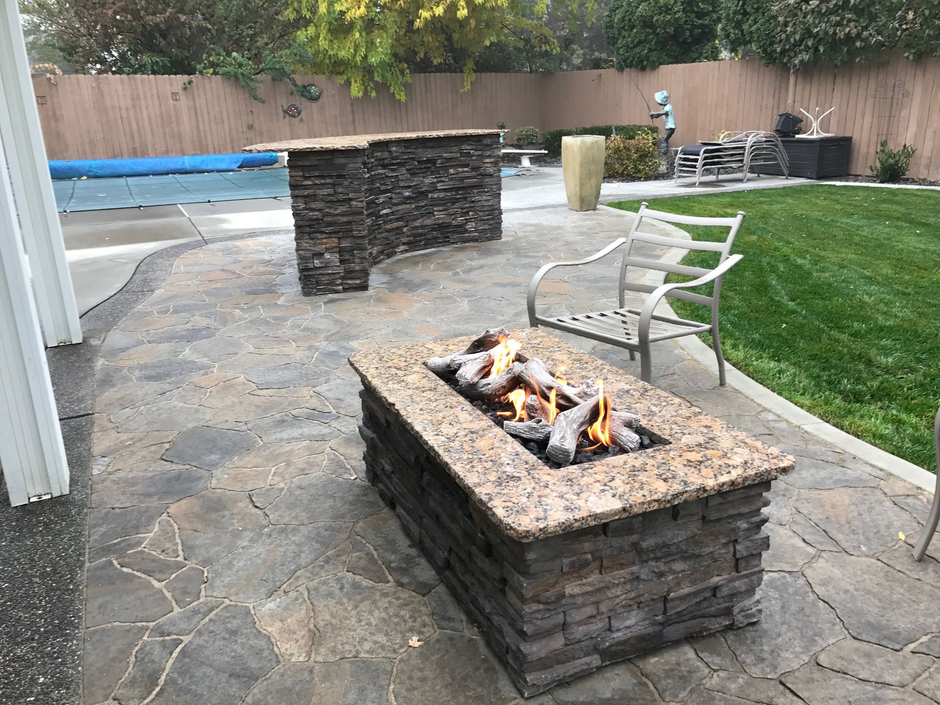 A fire pit is sitting on a patio next to a pool.