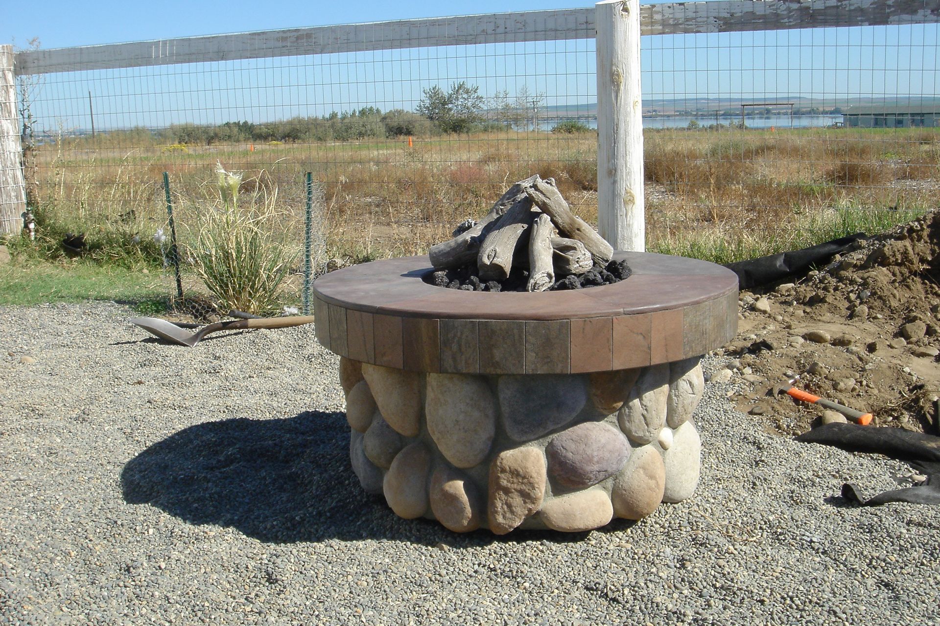 A fire pit surrounded by rocks in a gravel area