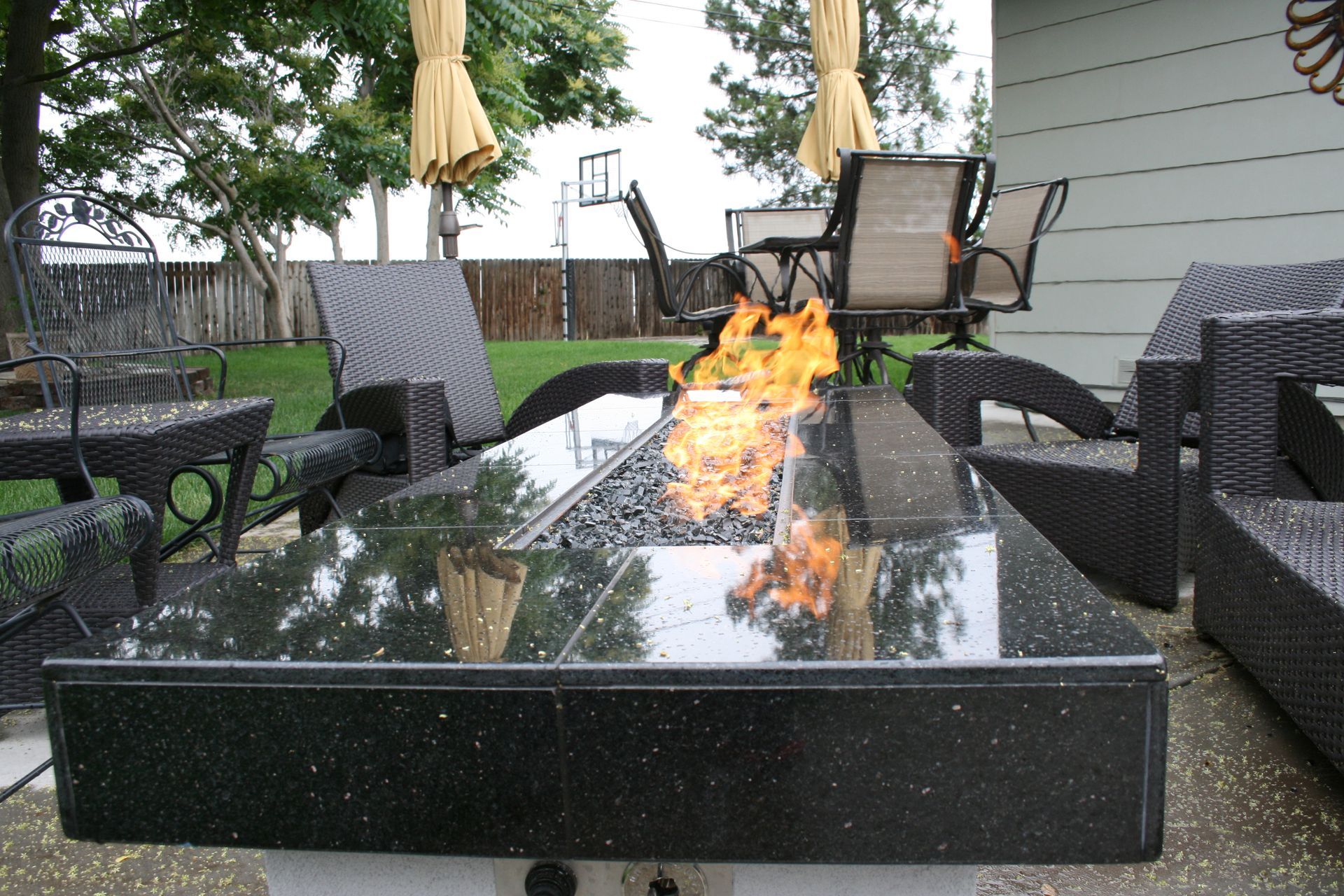 A fire pit in a backyard with chairs and umbrellas