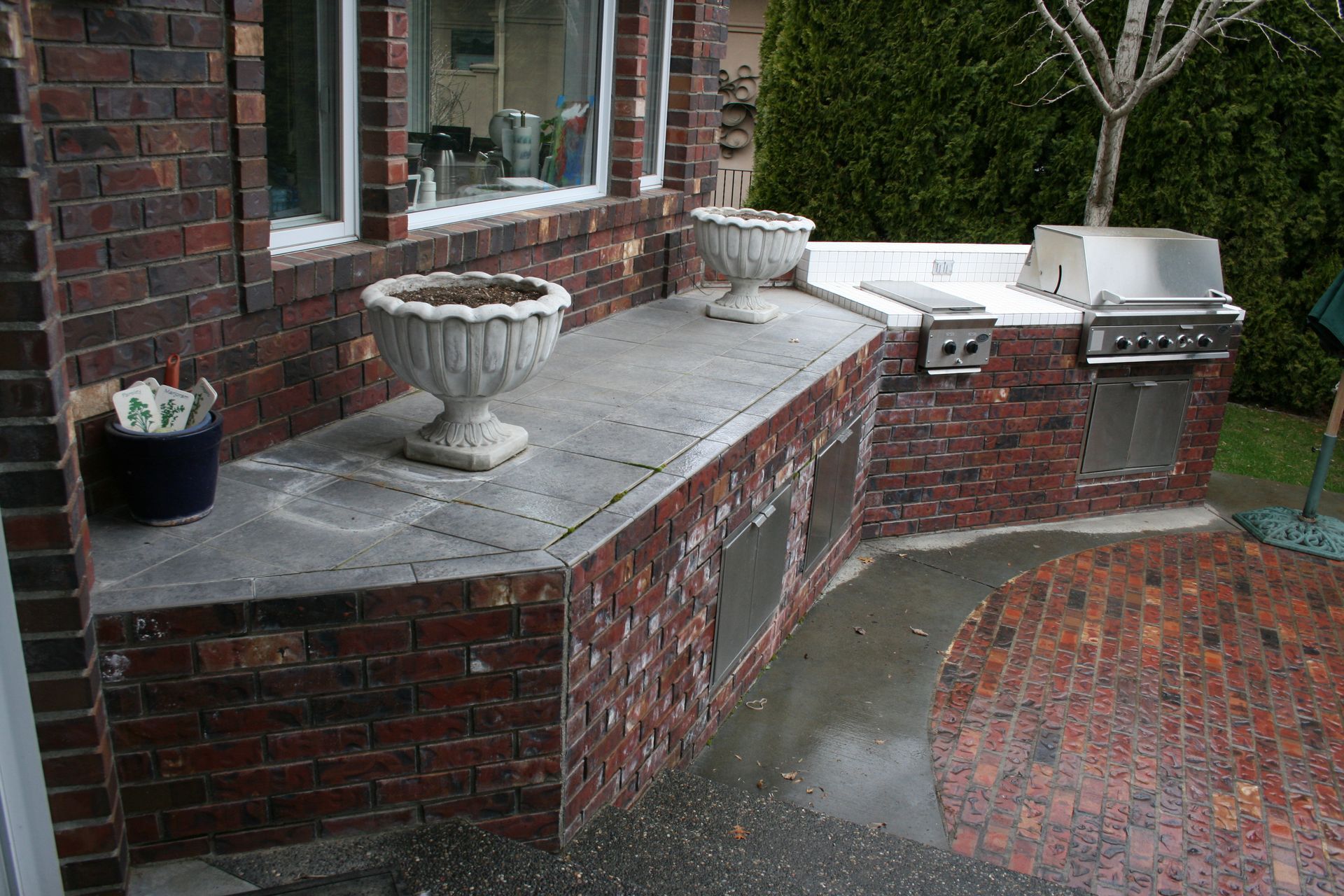 A brick patio with a grill and potted plants