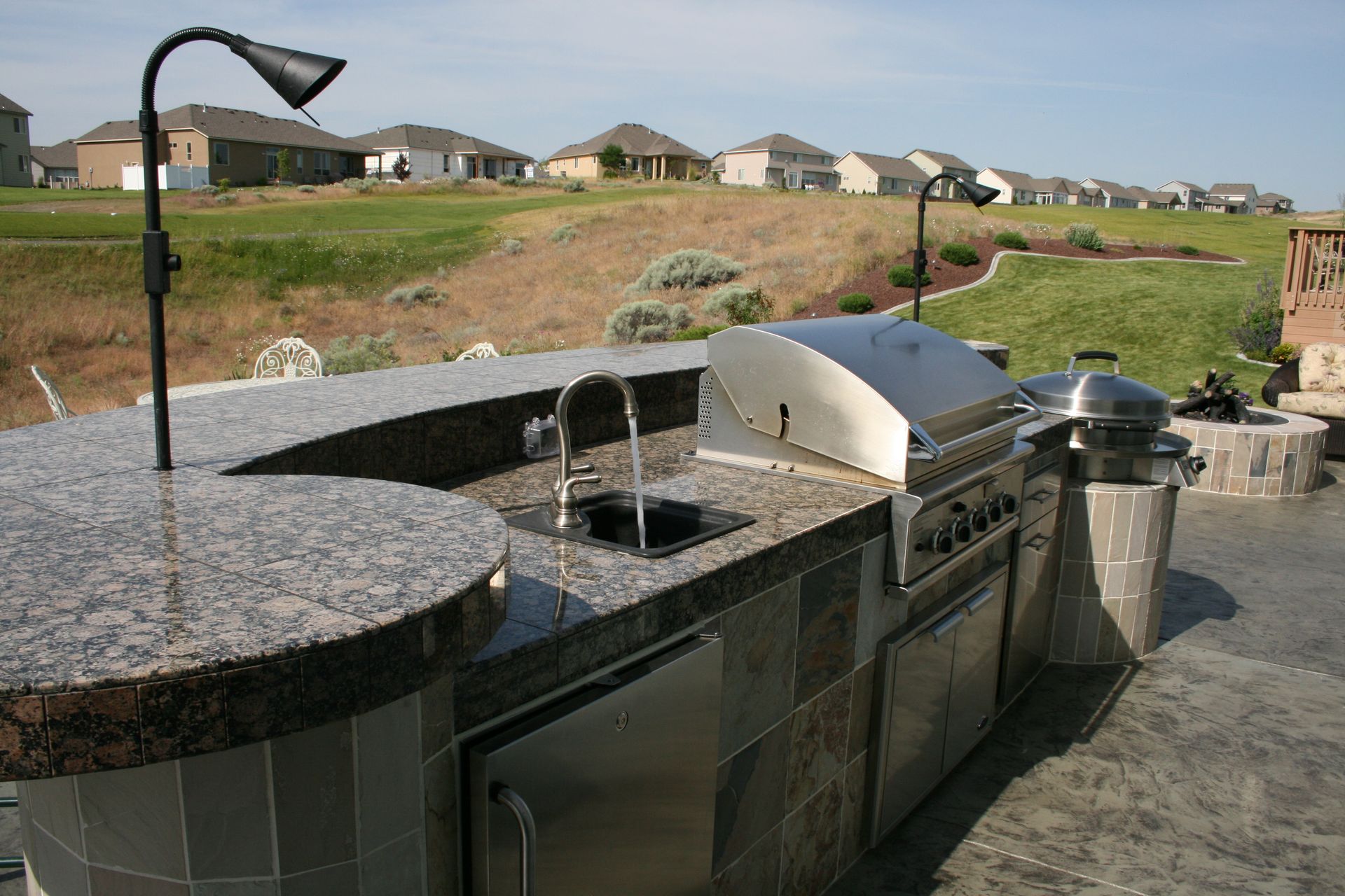 An outdoor kitchen with a grill and a sink