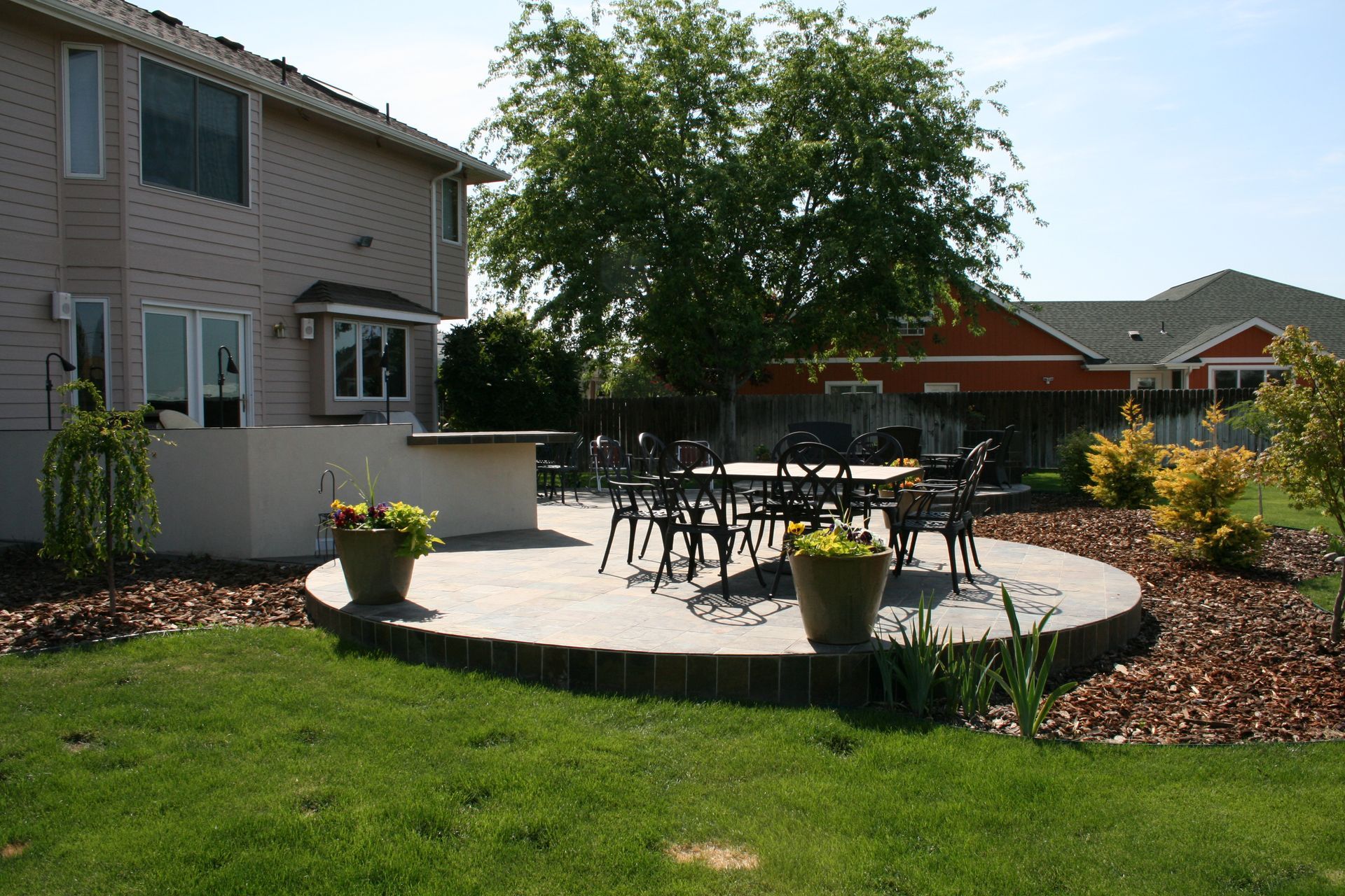 The backyard of a house has a patio with a table and chairs