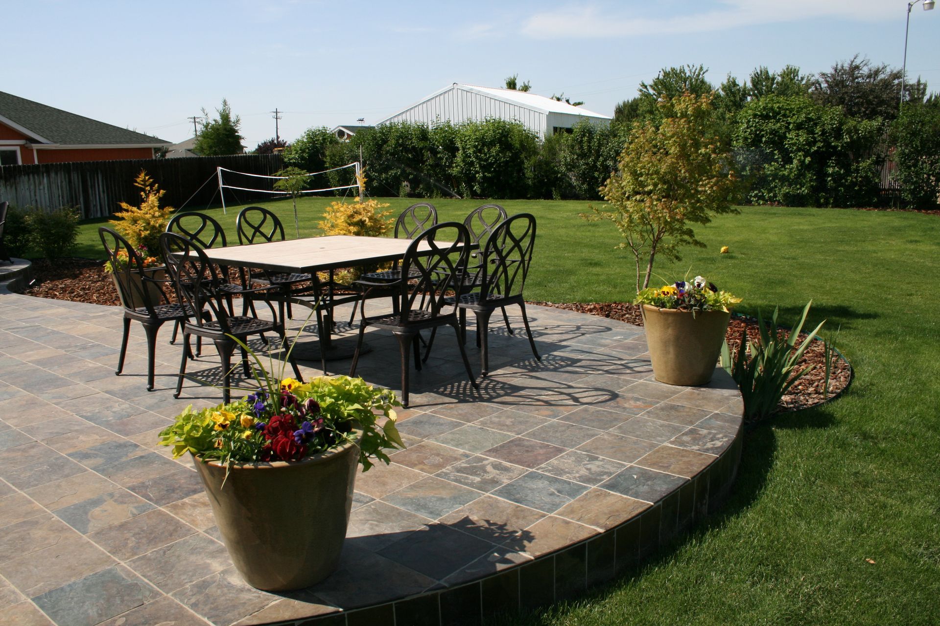A patio with a table and chairs and potted plants
