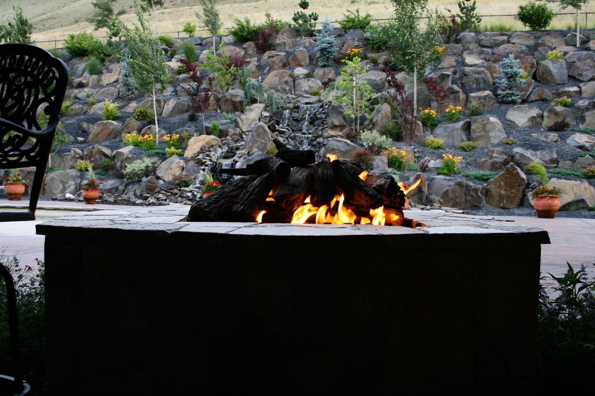 A fire pit is lit up in front of a rock wall.