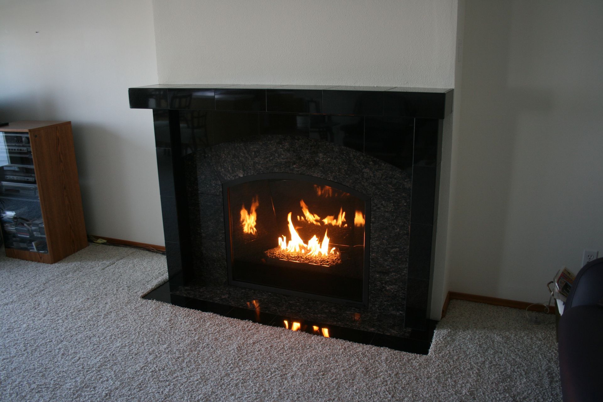 A fireplace is lit up in a living room.