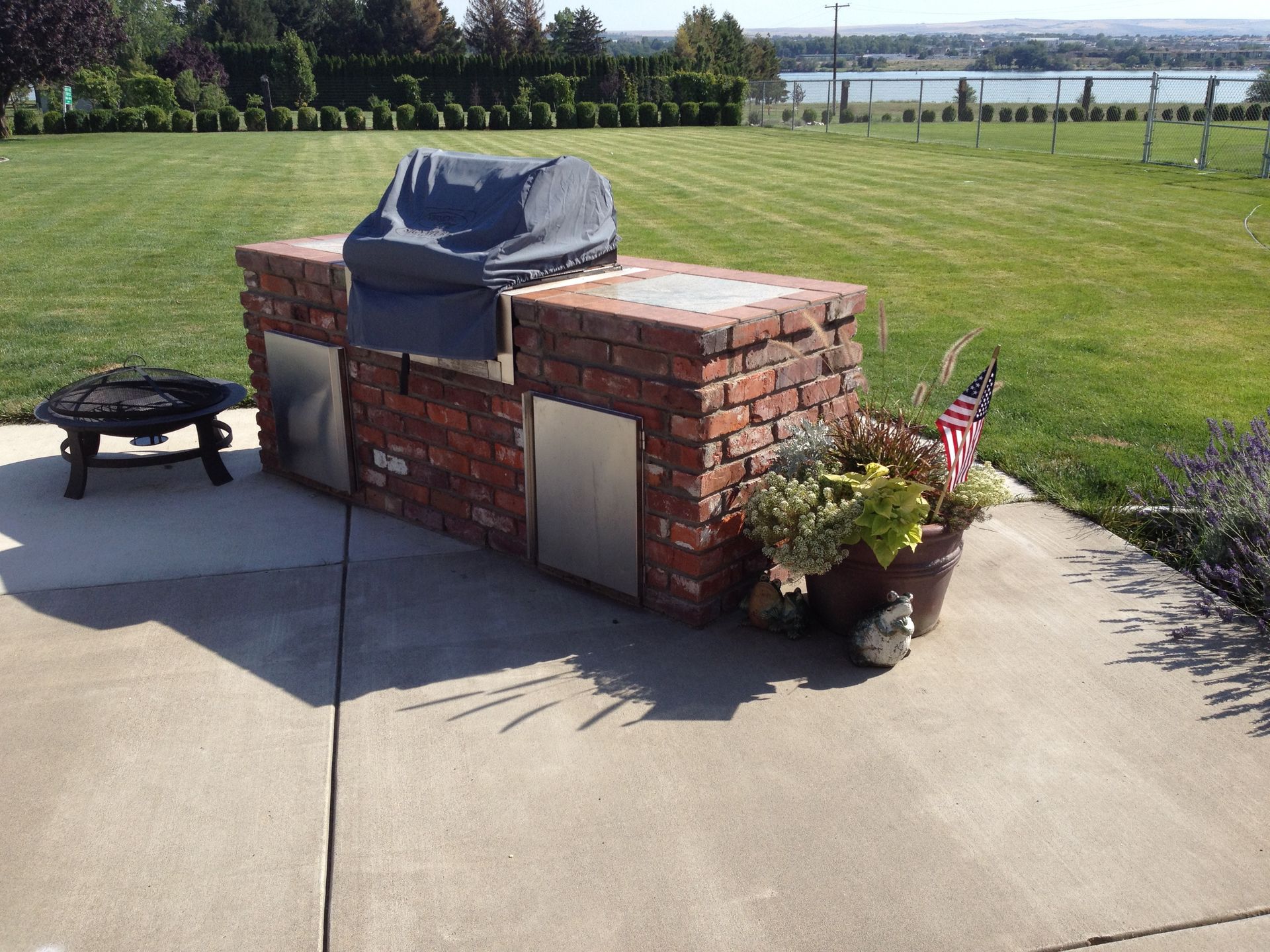 A brick grill is sitting on a patio next to a fire pit