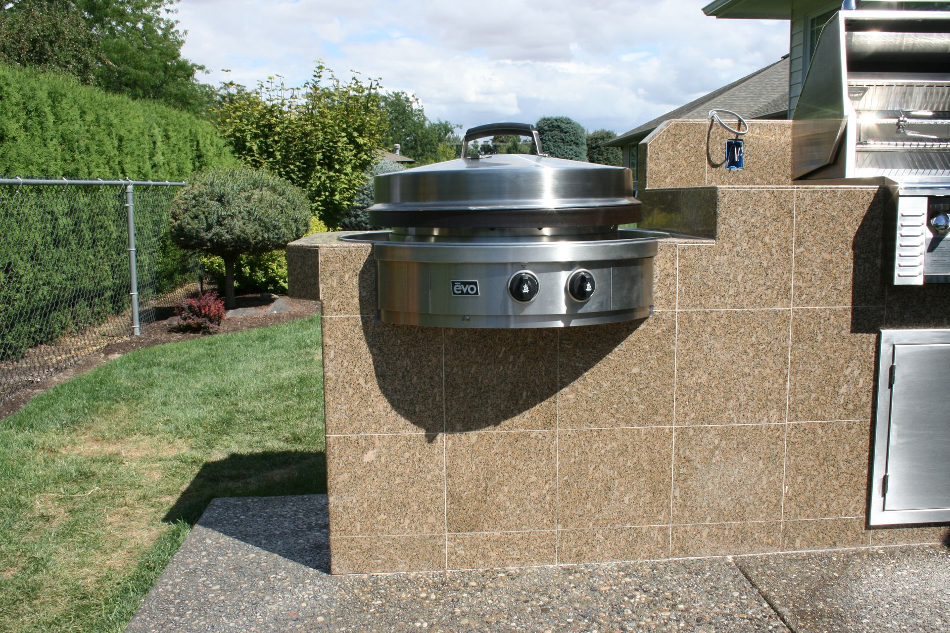A stainless steel grill is mounted to a brick wall