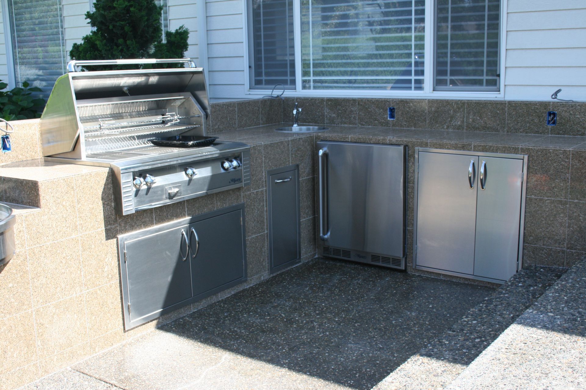 An outdoor kitchen with stainless steel cabinets and a grill