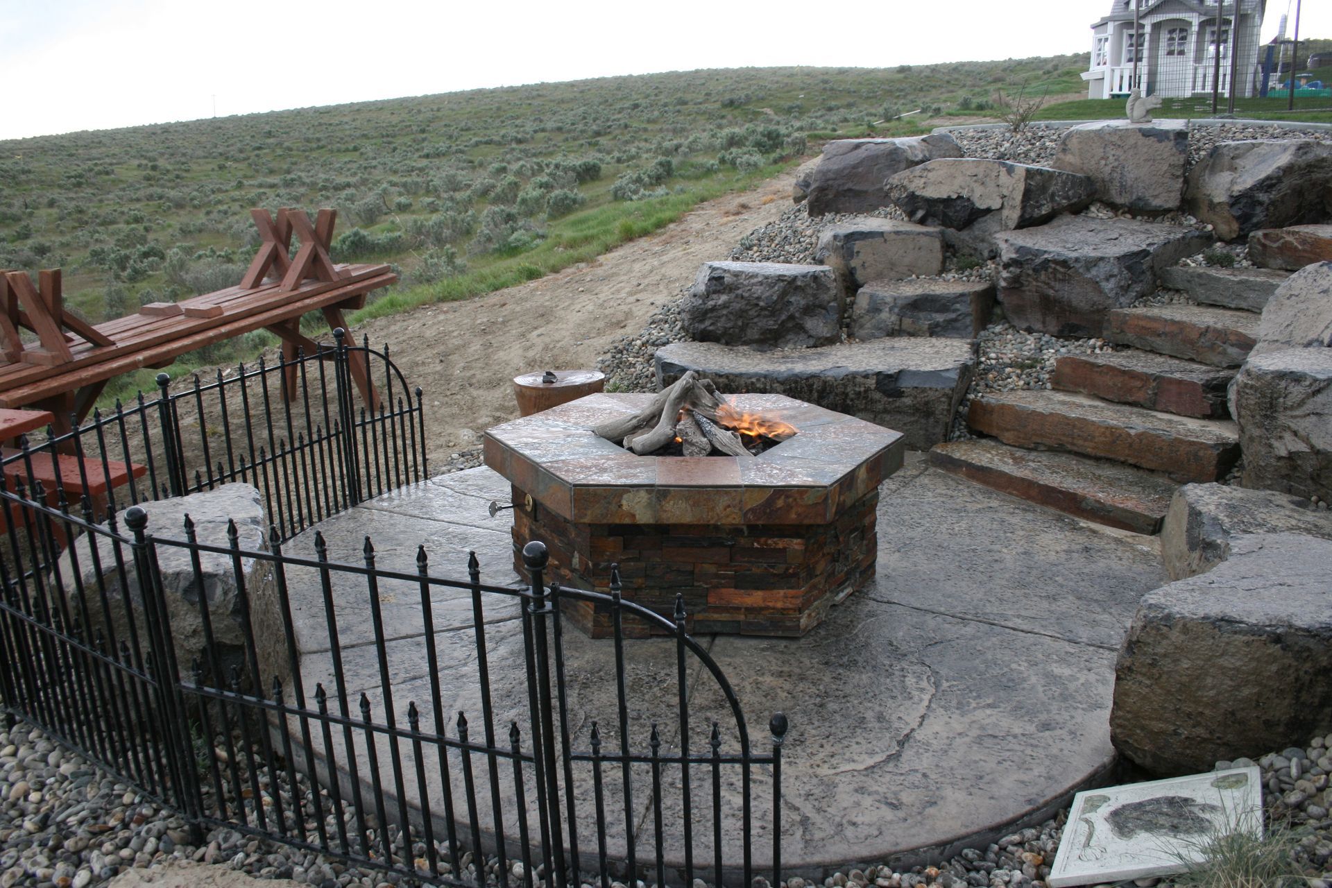 A fire pit is surrounded by a fence and stairs.