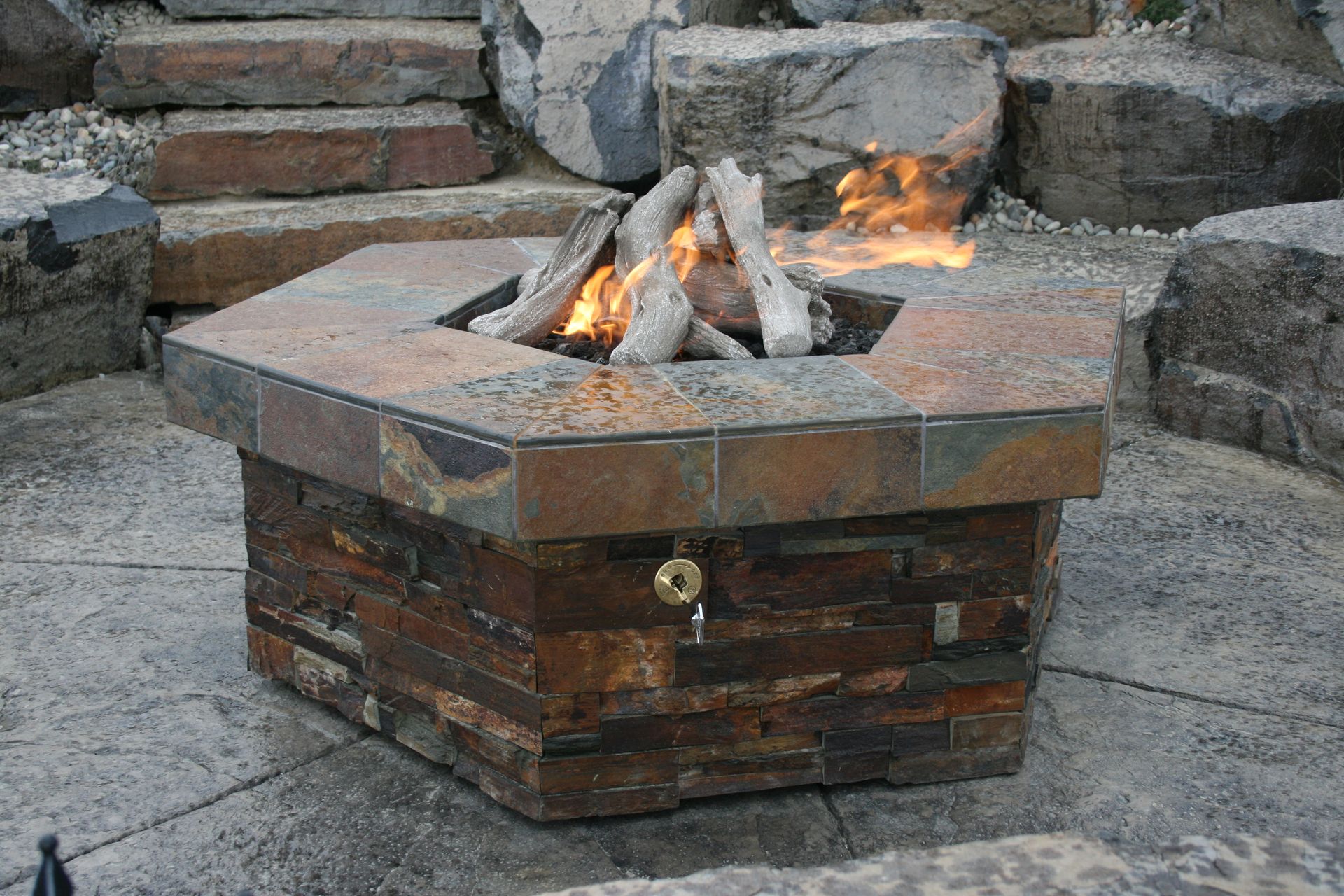 A fire pit is surrounded by rocks on a patio.
