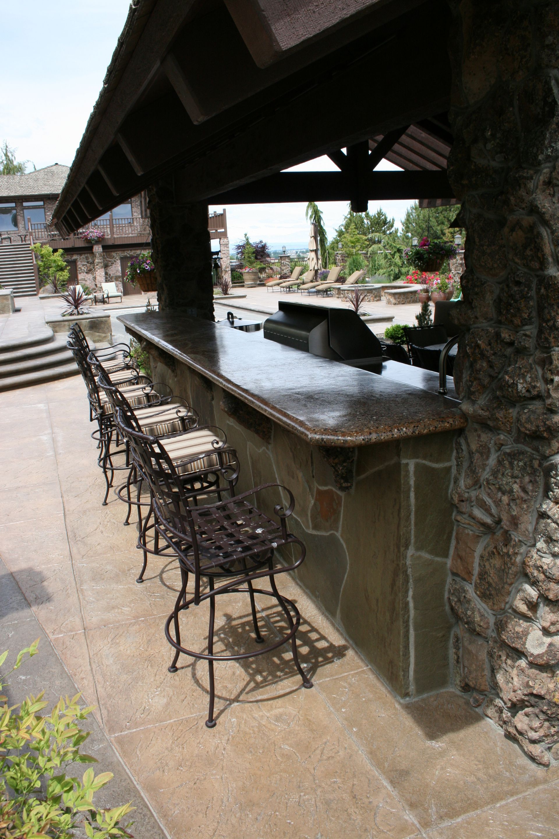 A patio with a bar and chairs under a roof