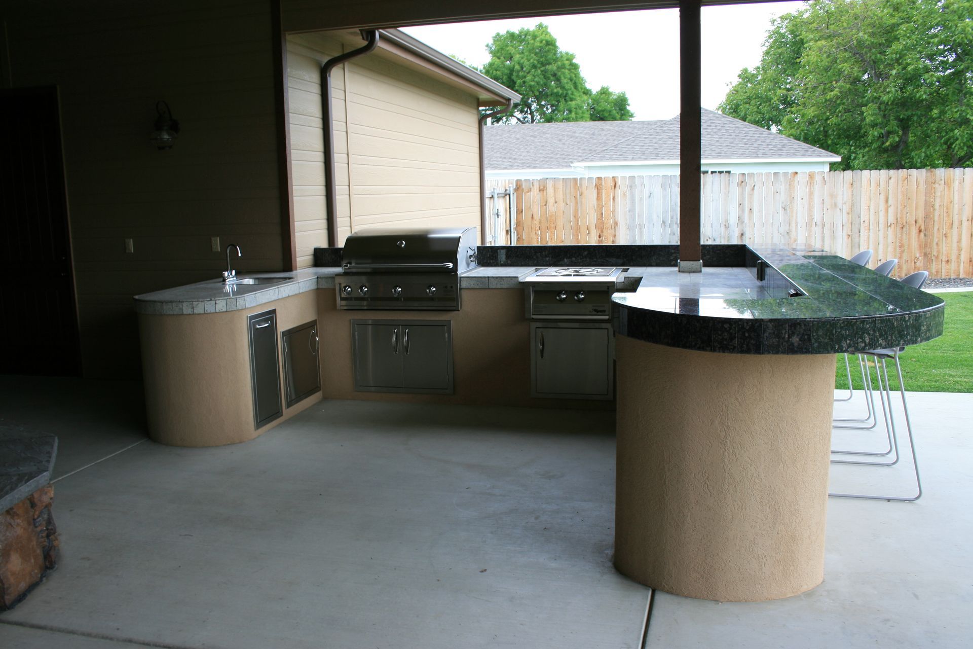 An outdoor kitchen with a grill and a bar