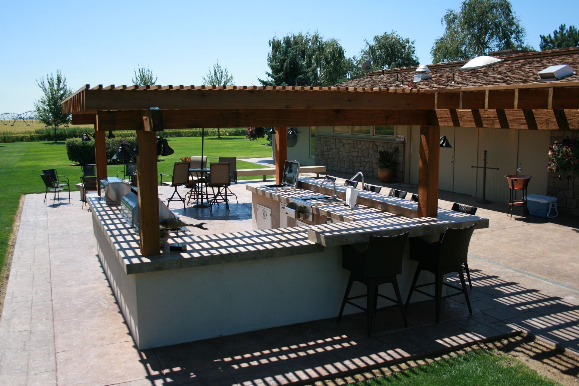 A large outdoor kitchen with a wooden pergola over it