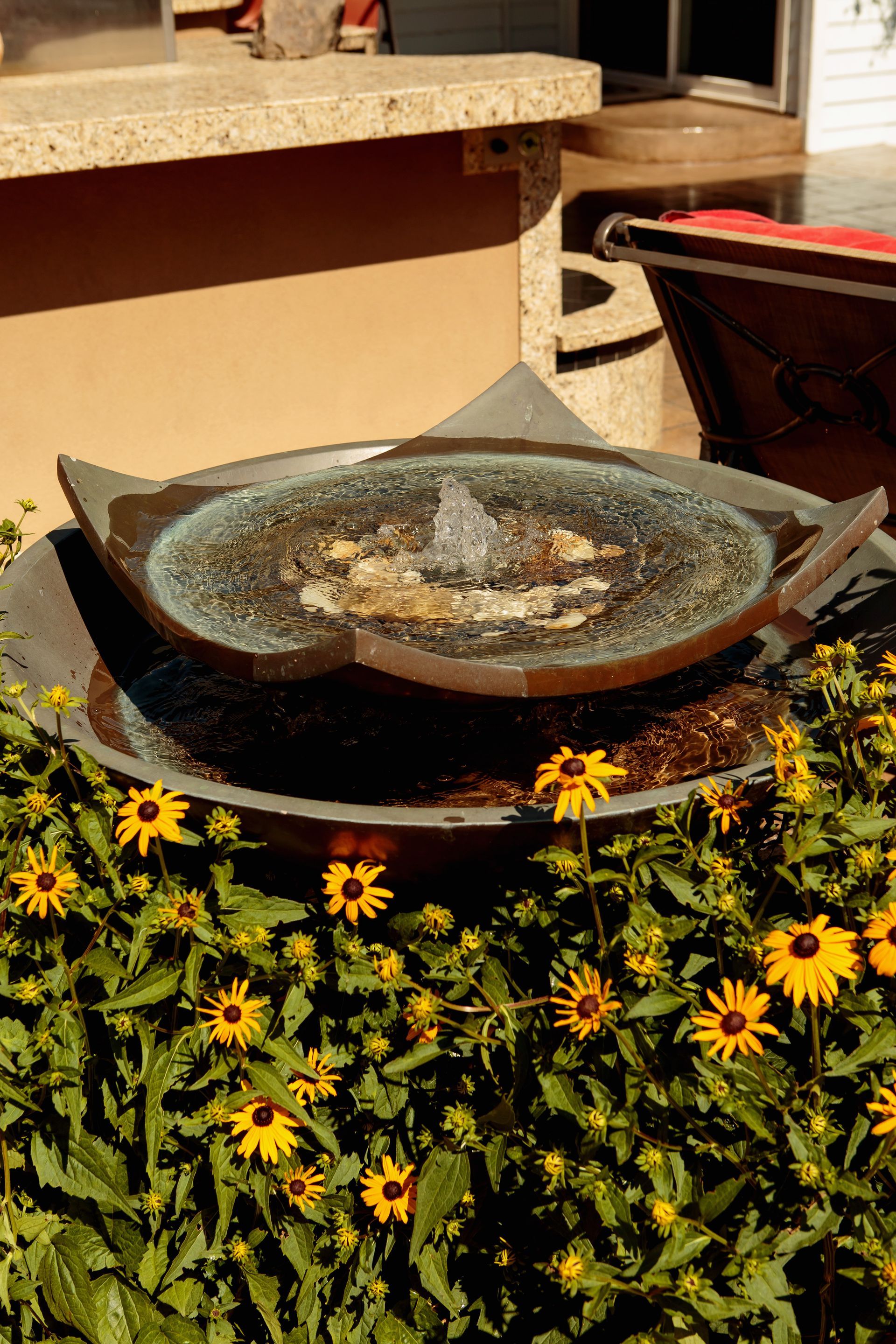 A fountain is surrounded by flowers in a garden.