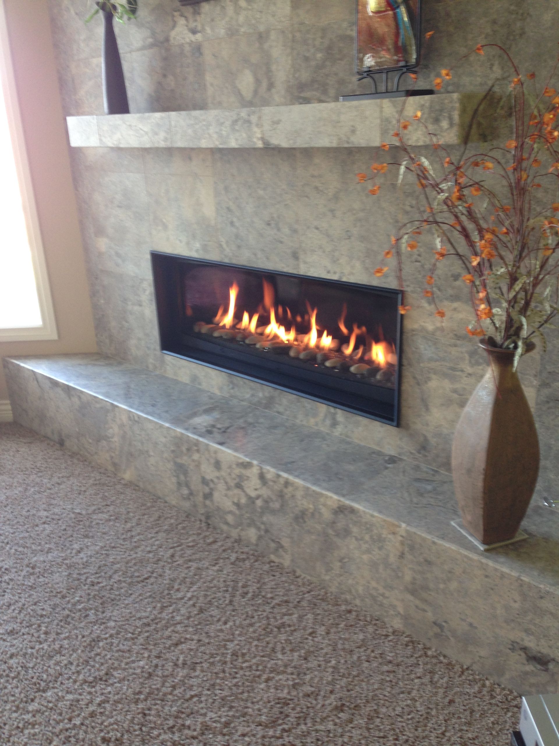 A living room with a fireplace and a vase of flowers.