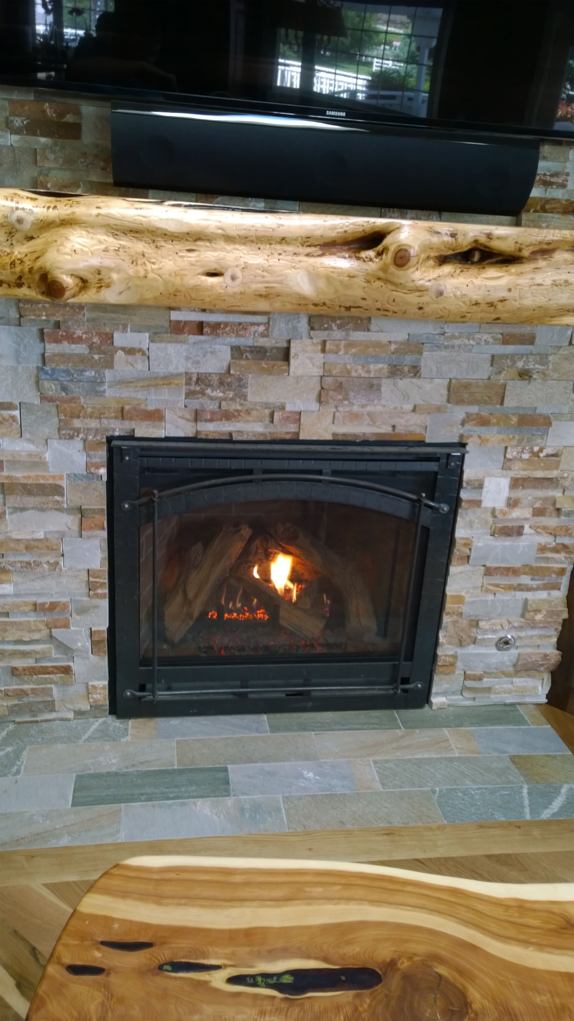 A fireplace with a wooden mantle and a wooden table in front of it.