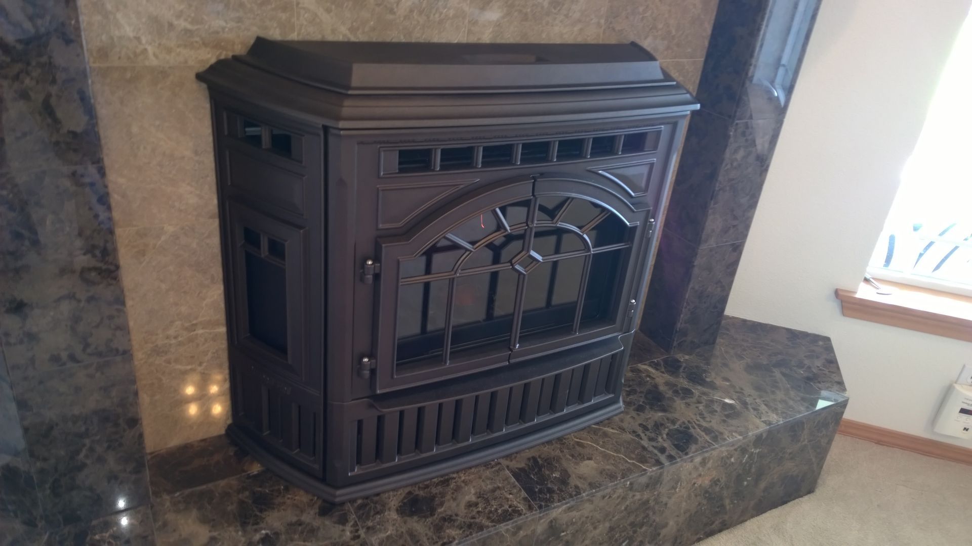 A wood stove is sitting on top of a marble fireplace.