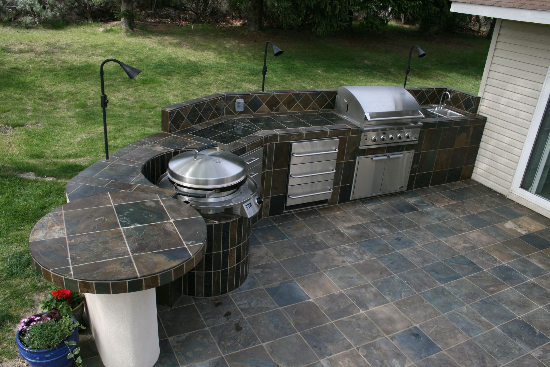 A large outdoor kitchen with a grill and a table