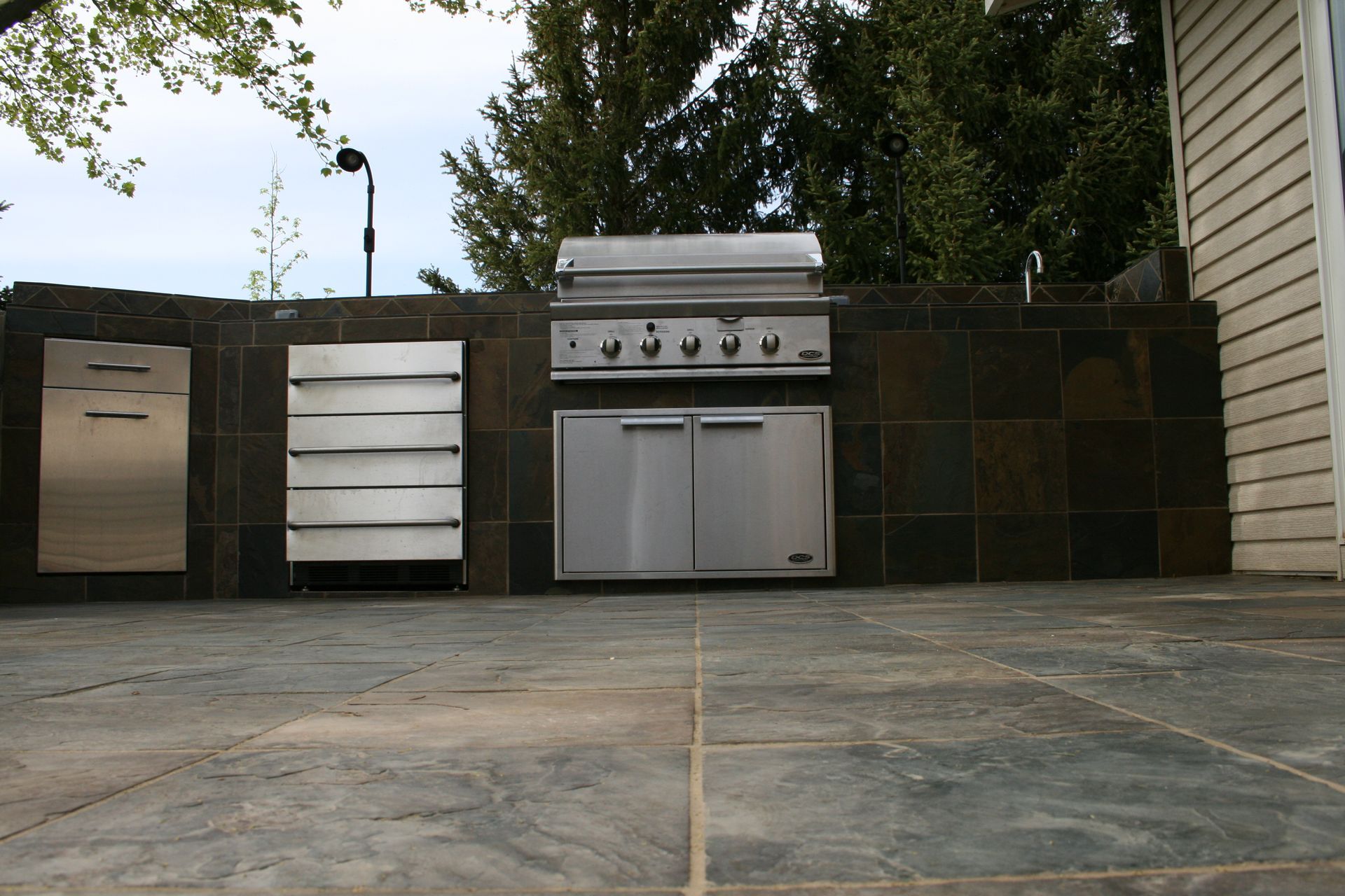 A stainless steel grill is built into the side of a house